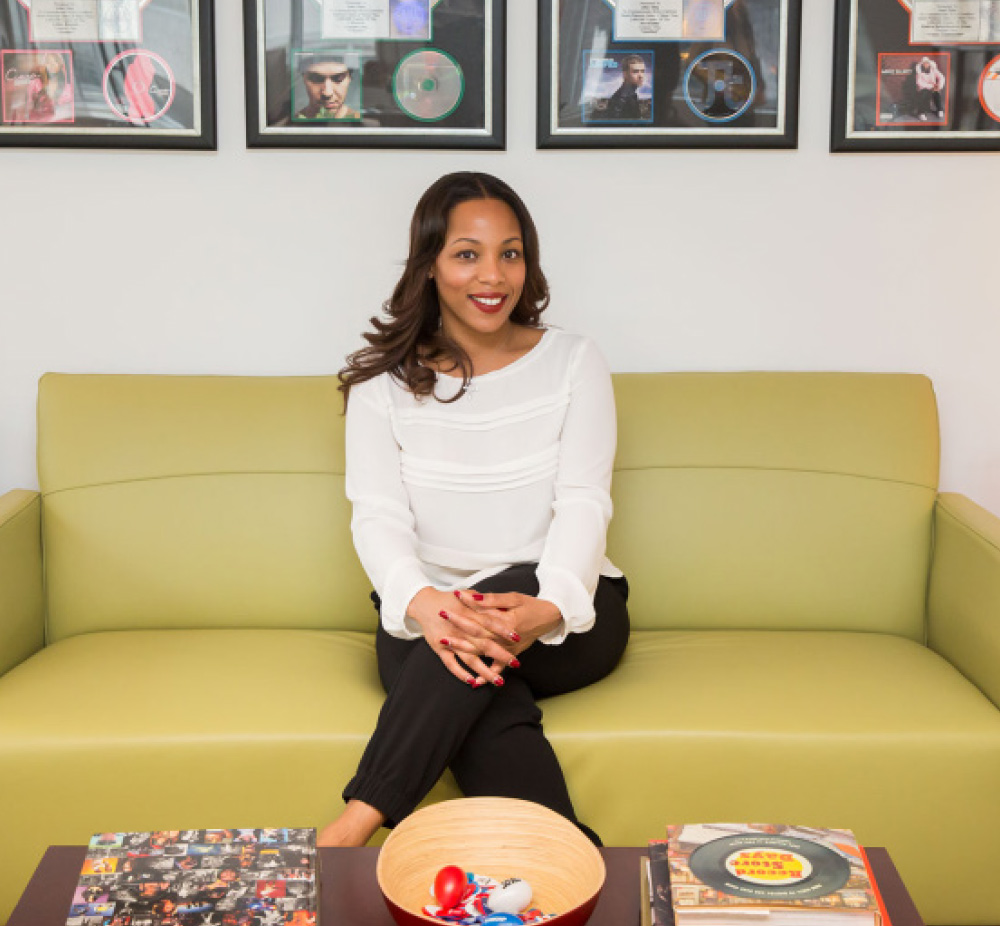 Nicole George-Middleton sitting on green couch and posing for a photo